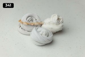 Three white fabric wraps with decorative trim on light gray surface.