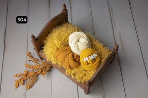 Wooden bowls with yellow and white textured fabrics arranged on a rustic white wooden floor.