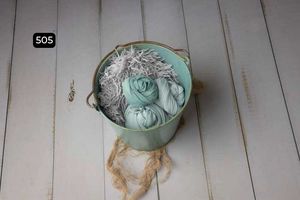 Mint green and white textured materials arranged in wooden bowls on light wooden planks.