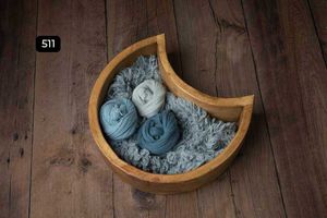 Curved wooden bowls with blue and grey textiles photographed on dark wooden flooring.