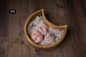 Crescent-shaped wooden bowls with soft pink fabrics on rustic wooden flooring.