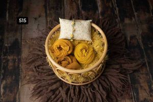 Wooden bowls containing warm yellow textiles on dark rustic surface.