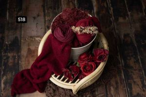 Deep burgundy roses and delicate white flowers arranged in vintage containers against a dark rustic background.