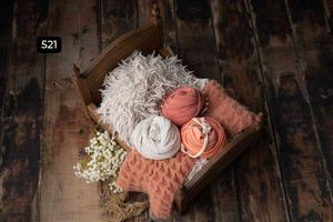 Soft pink and white floral arrangements displayed in antique vessels on a dark wooden surface.