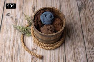 Coiled rope baskets with yarn and textile materials on weathered wooden background.