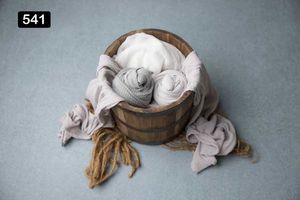 Wooden bowl filled with white and gray fabric wraps with some spilling onto gray surface.