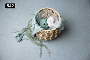 Woven basket with mint green fabrics and delicate floral arrangements on gray background.