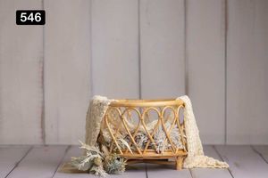Wooden crib with cream colored fabric and lace details against white paneled wall.
