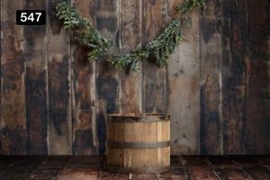 Wooden barrel with evergreen garland against weathered wooden wall.