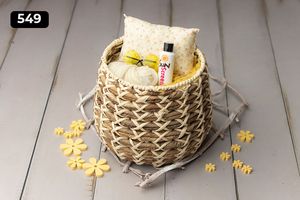 Woven basket containing pillow and yellow decorative elements on gray wooden floor.