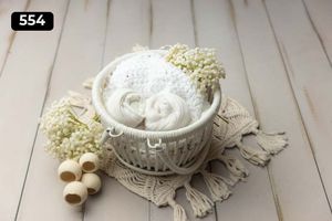 White decorative basket containing fabric wraps with wooden beads and lace accents.
