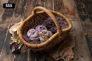 Woven brown basket containing purple fabric wraps on dark wooden surface.