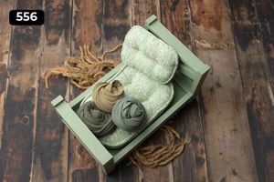 Mint green wooden bed prop with neutral colored fabric wraps on rustic wooden surface.