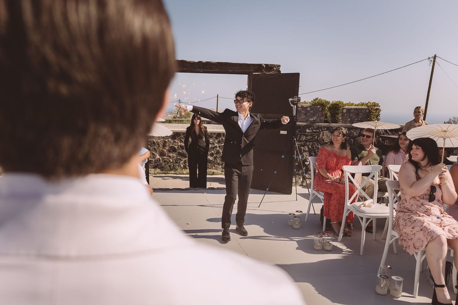 A groomsman at a destination wedding in Santorini makes his entrance to El Viento.