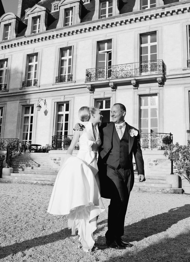 Bride and groom walking in front of Château de Santeny during their wedding near Paris