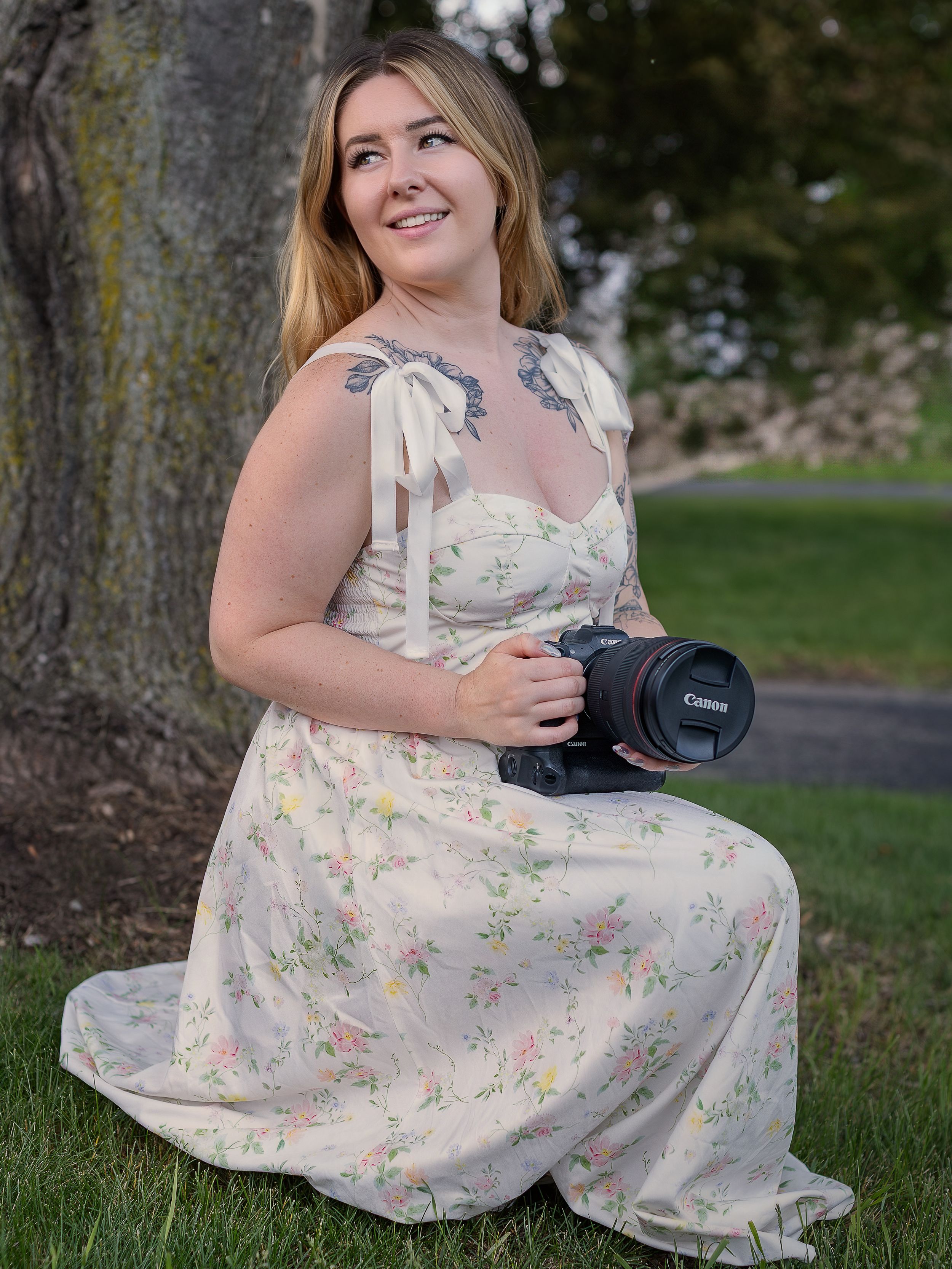 Portrait of woman with long wavy hair and tattoos in soft natural lighting.