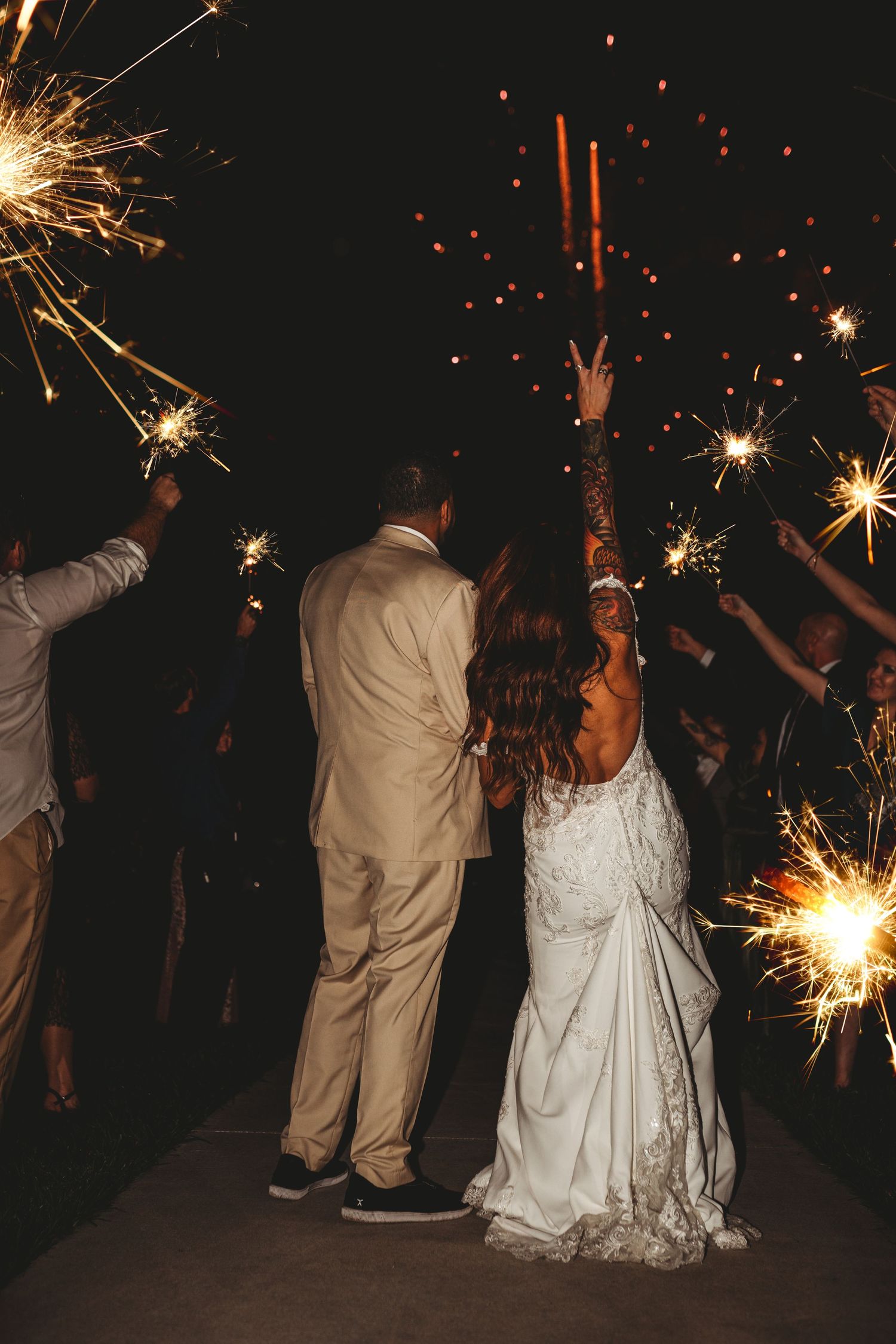 Wedding couple and guests celebrate with sparklers during nighttime festivities.