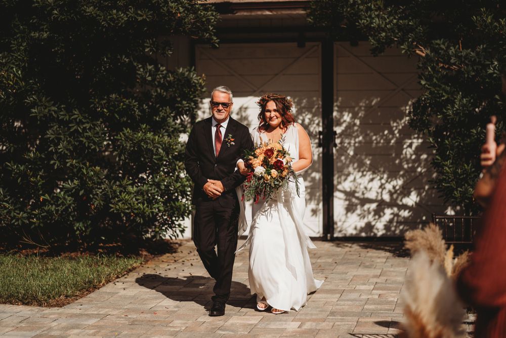 A couple walks down a stone pathway during a wedding procession.