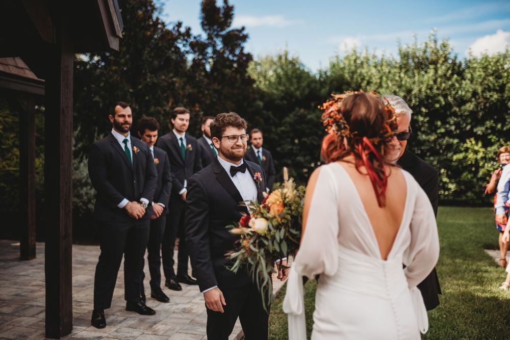 A wedding party stands in formation during an outdoor ceremony.