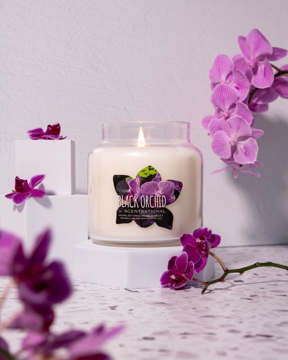 Candle product photography with orchids and terrazzo backdrop