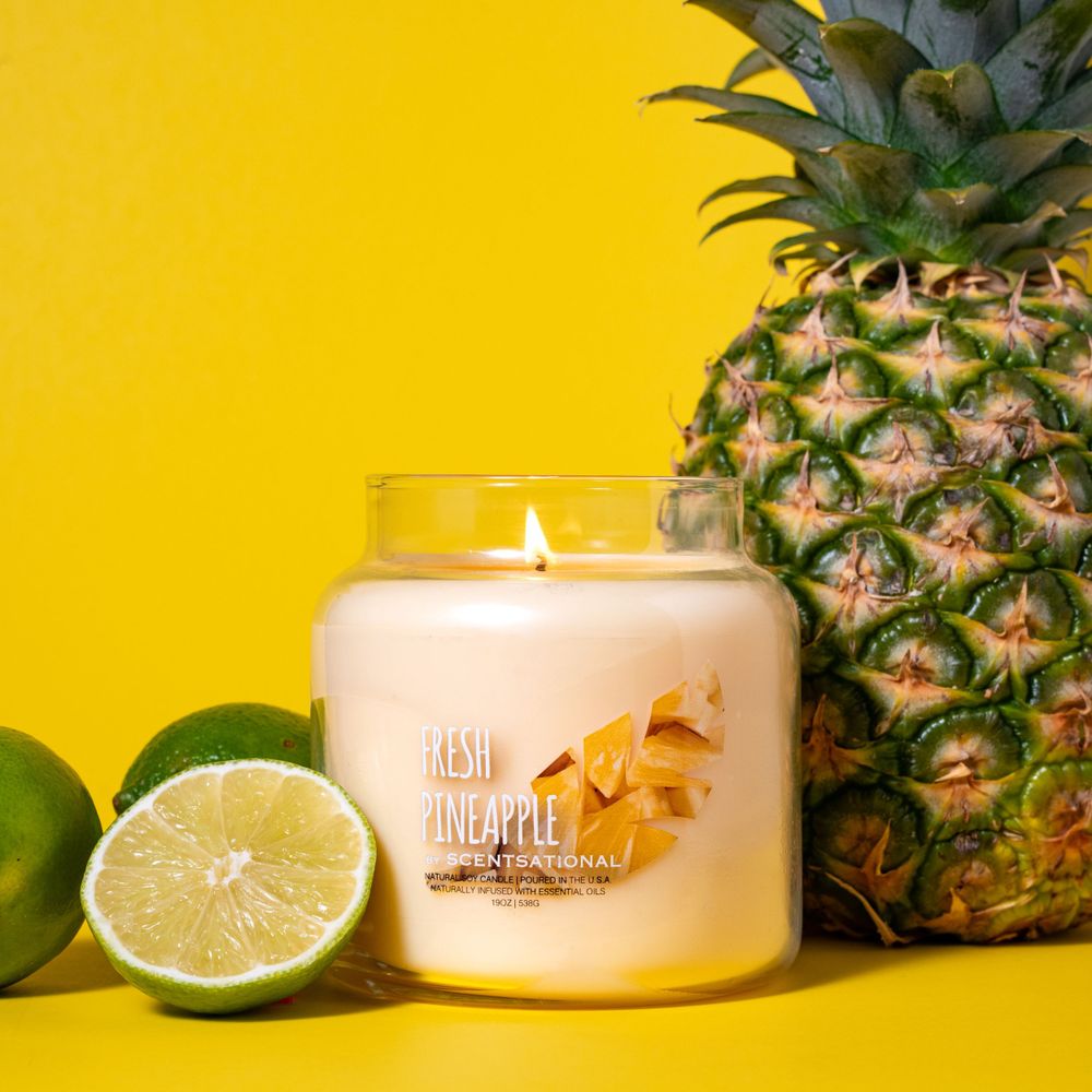 Candle product photography with tropical fruit limes pineapple and yellow backdrop