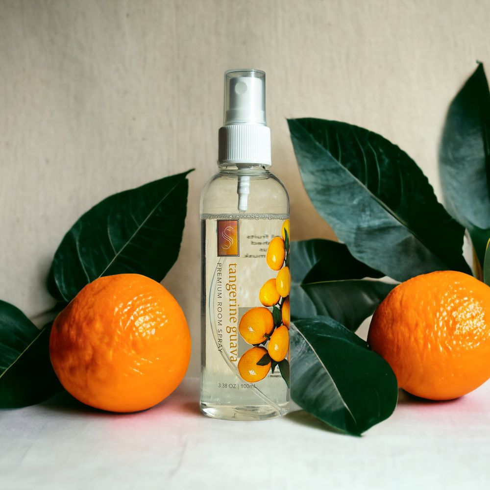 Orange citrus fruits and green leaves arranged with a spray bottle product on light background.