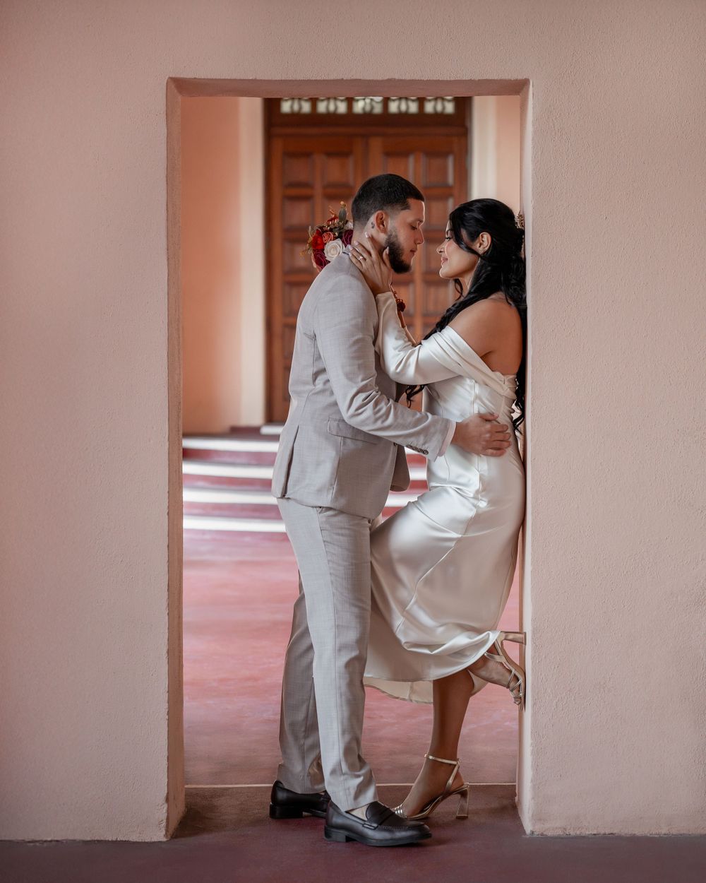 Intimate wedding portrait of couple embracing in pink archway at Sarasota Courthouse in Sarasota, Florida.