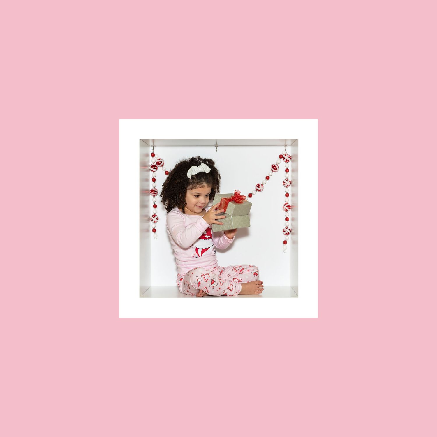Valentine's themed photo in a white frame with heart garland against pink background.