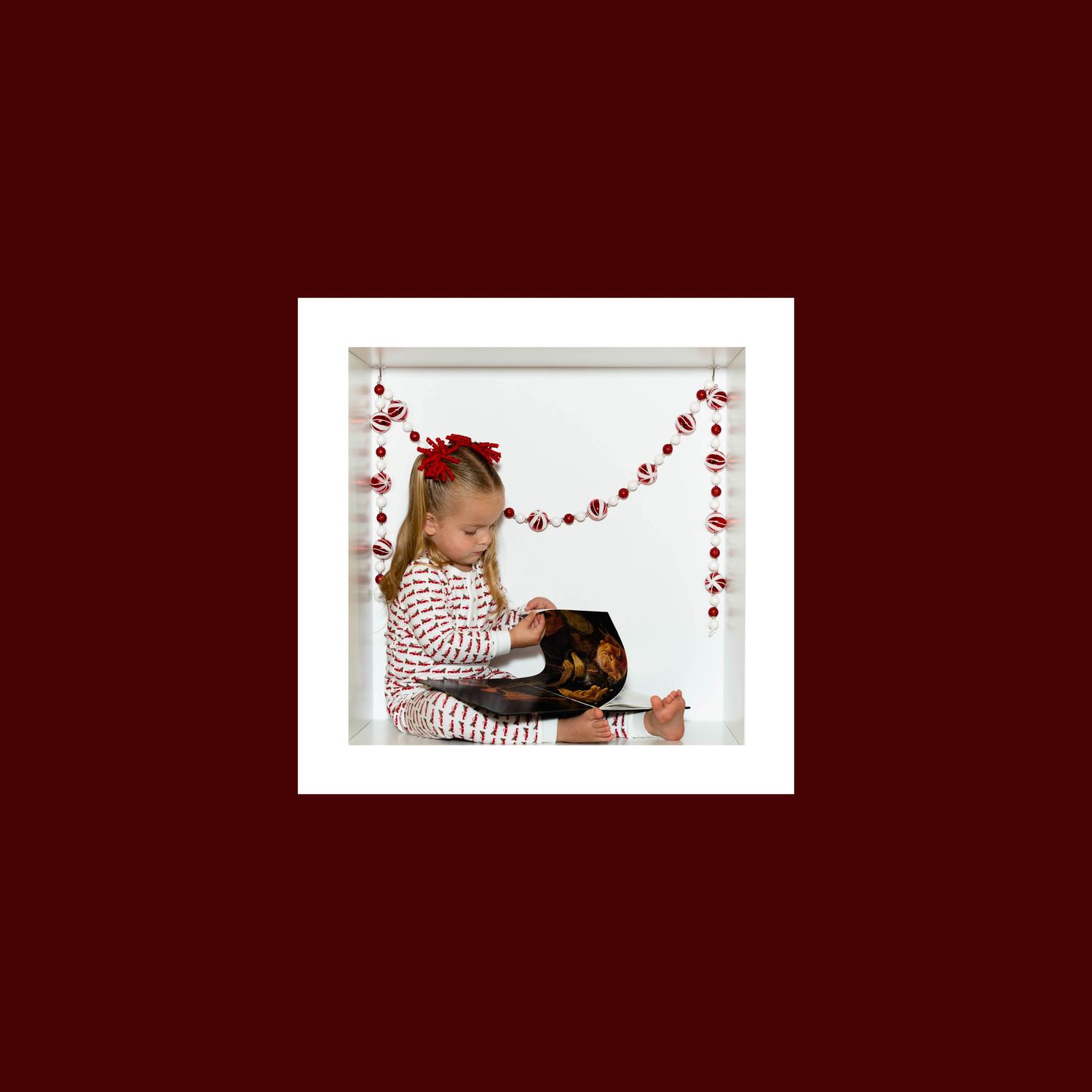 Holiday photo with red heart garland decorations against deep burgundy background.