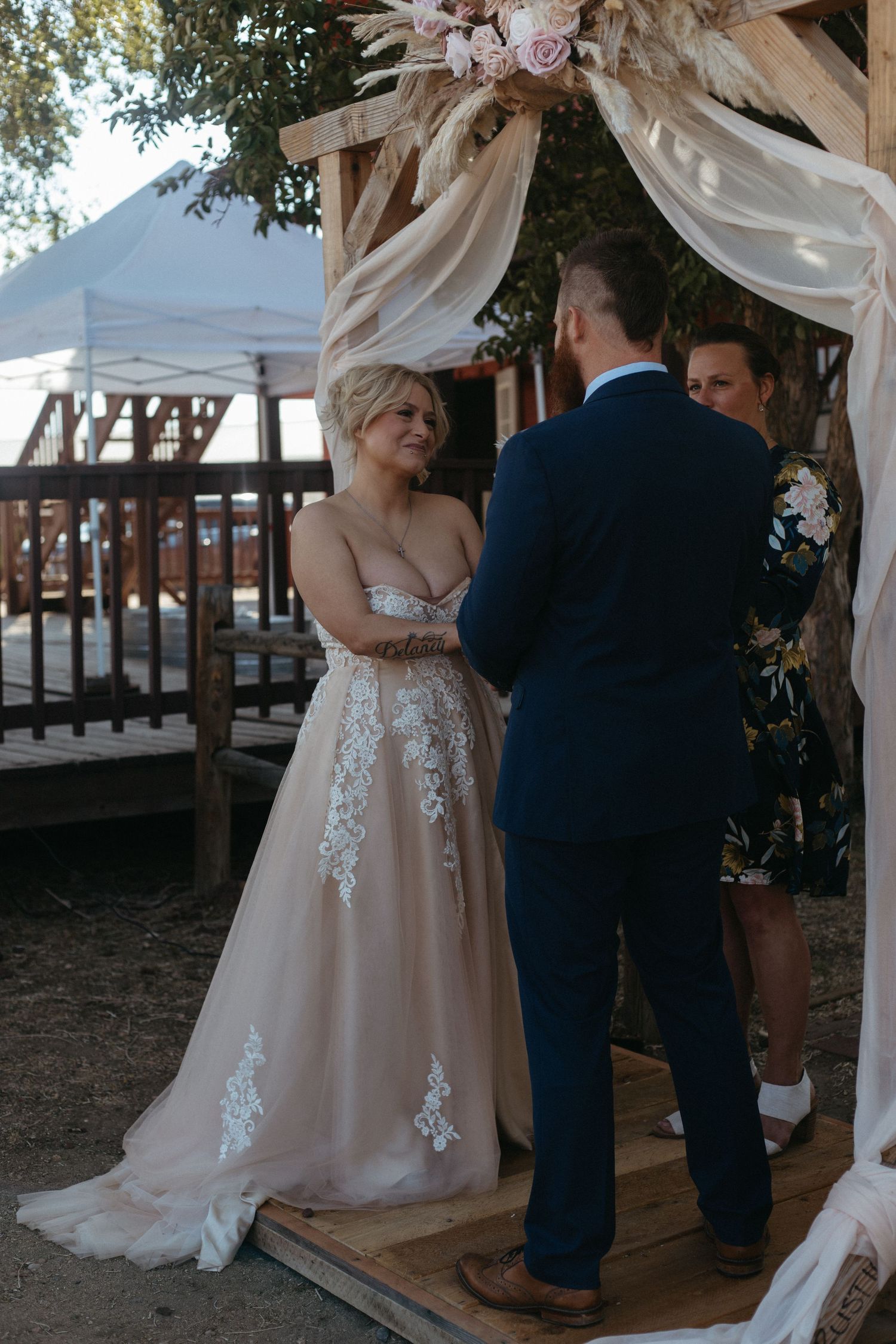 A couple shares their first dance under a floral wedding arch.