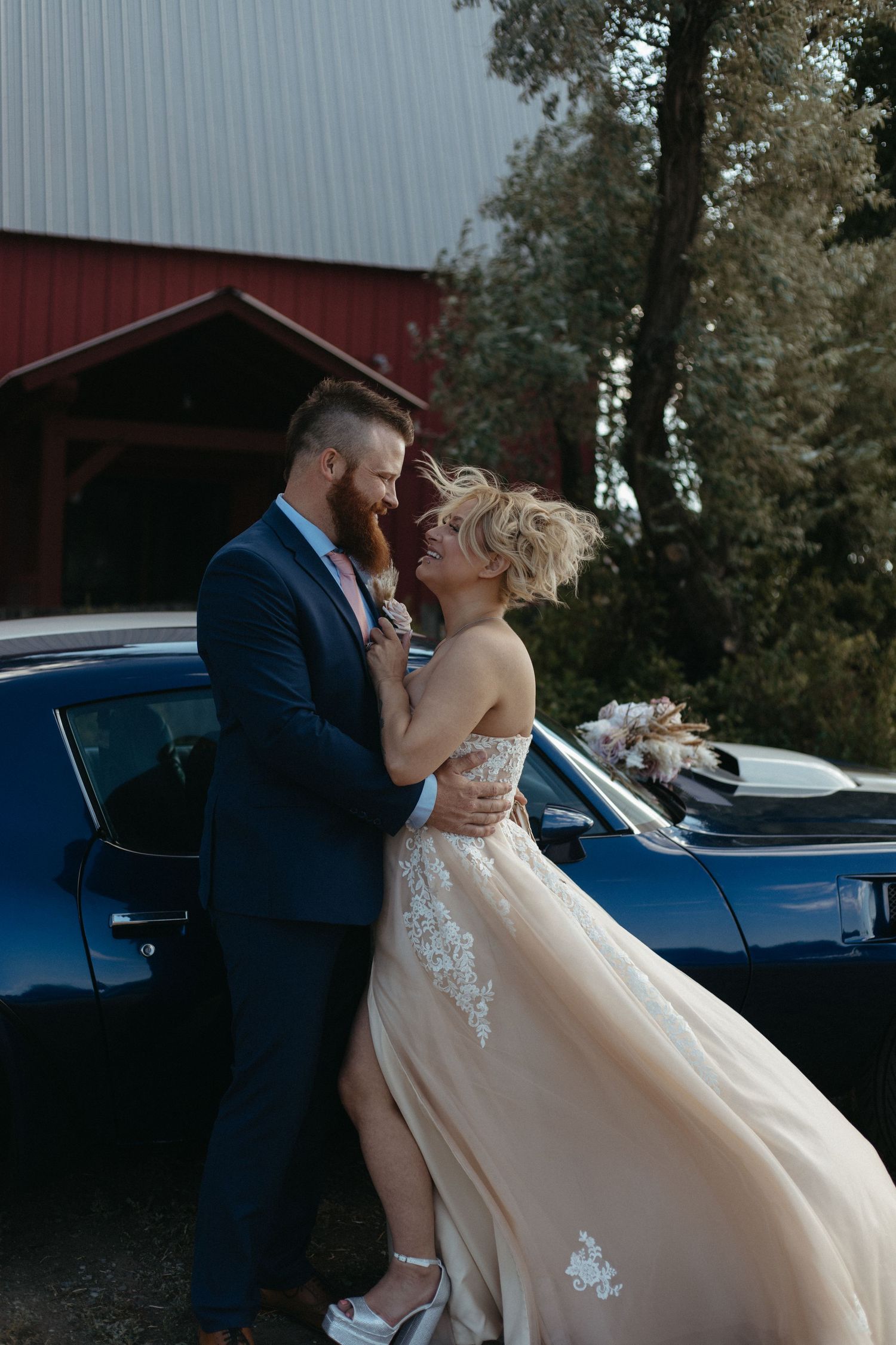 An intimate wedding photoshoot featuring a flowing champagne dress and blue car backdrop.