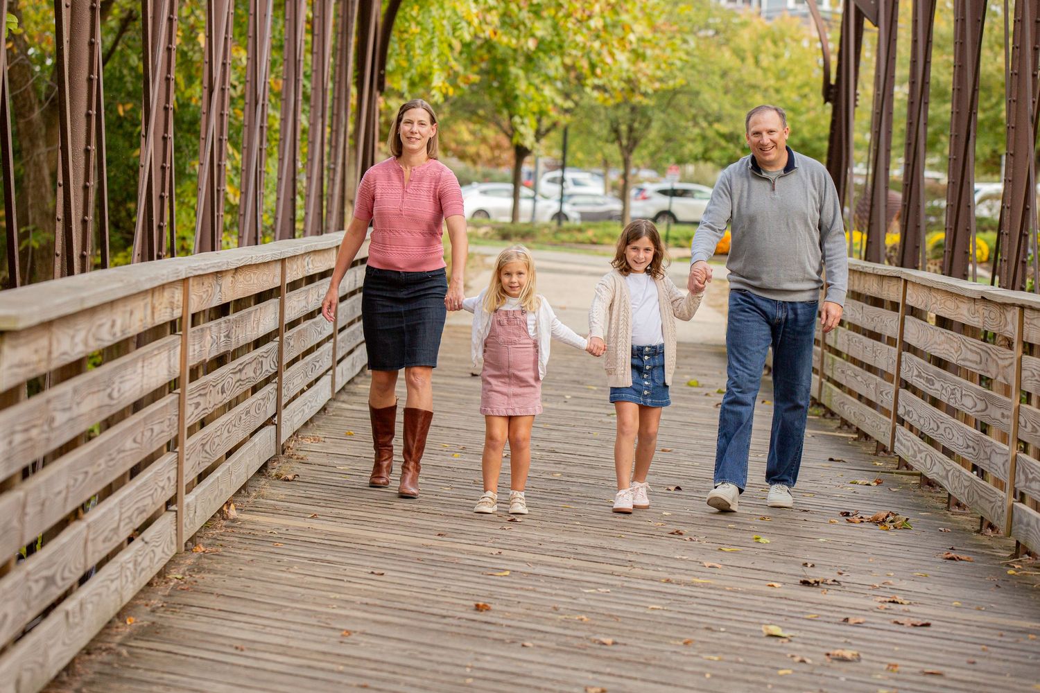 Black and white family portrait of six people standing together on a wooden bridge in a forest setting.