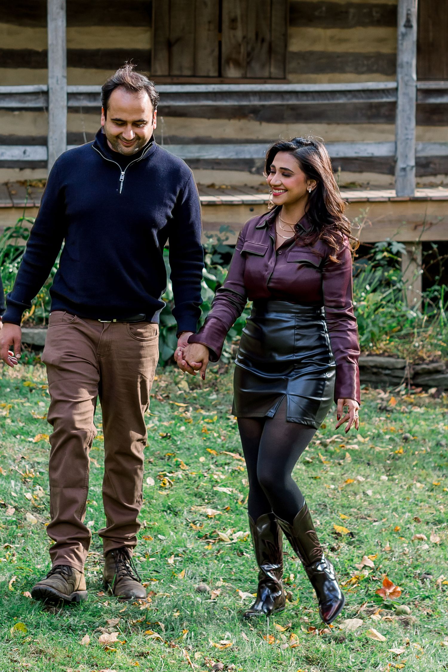 Playful couple walking and interacting on grass with fall leaves.