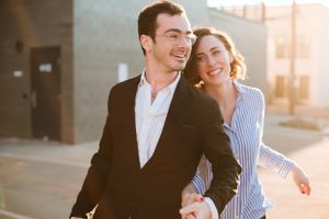 Couple laughing together outdoors during golden hour in urban setting.