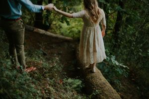 Helping hand extended on forest path as person balances on fallen log.