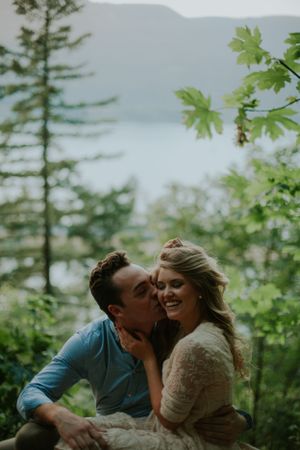 Intimate moment shared among trees with mountain lake vista in background.