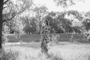 Black and white portrait of someone standing in a misty field.