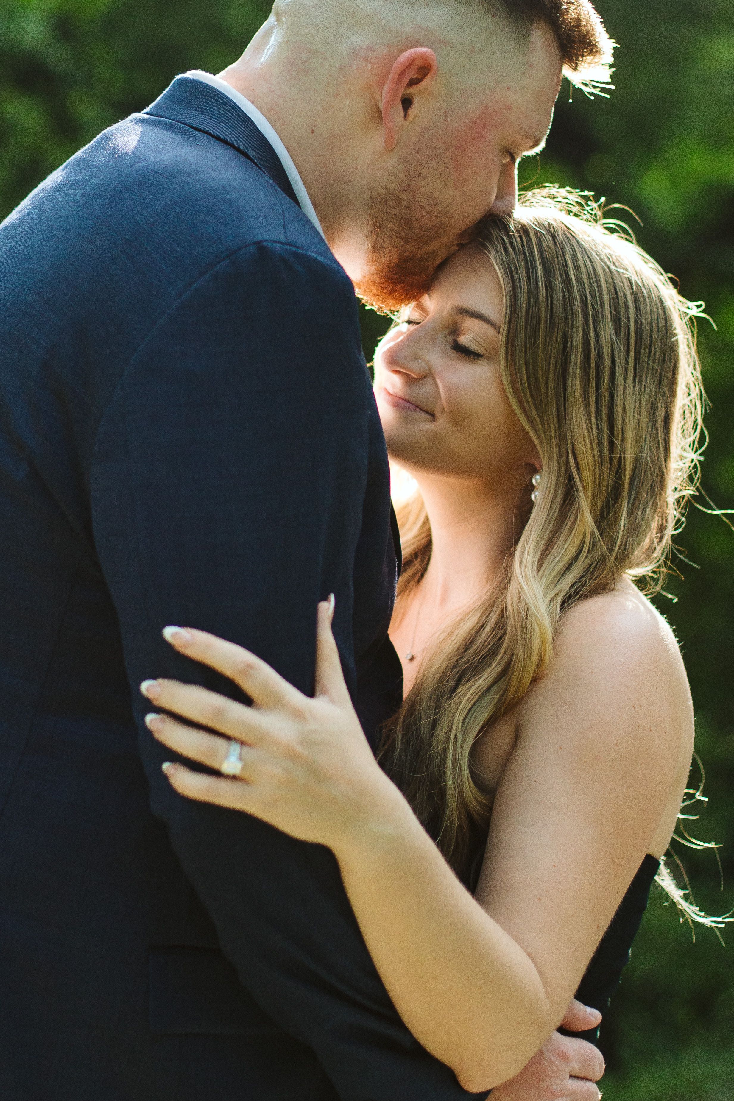 Romantic couple embracing outdoors in formal attire during an intimate moment.