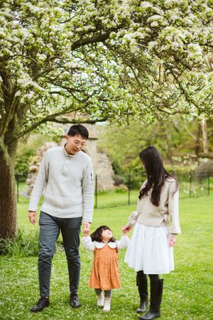 A family enjoys a spring day under blooming trees in a garden setting.