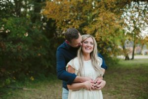 A couple shares a tender moment outdoors during autumn.