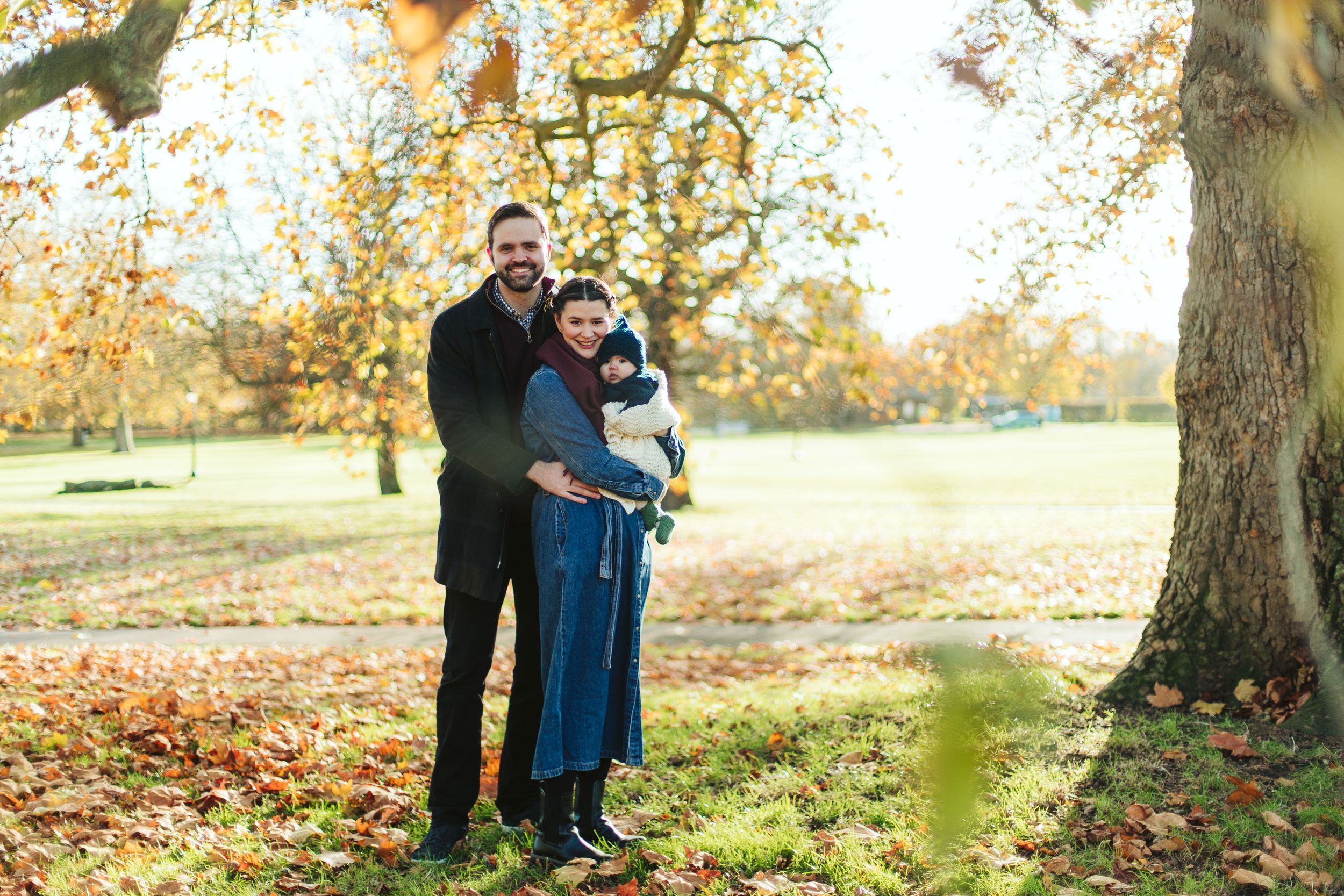 Family enjoying an autumn day together under golden trees in a park.