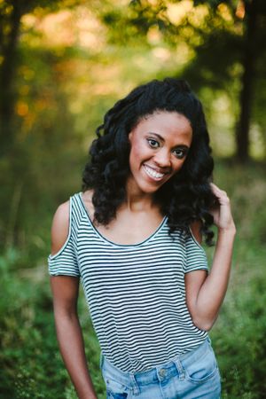 Person in striped cold-shoulder top poses outdoors with natural sunset lighting.