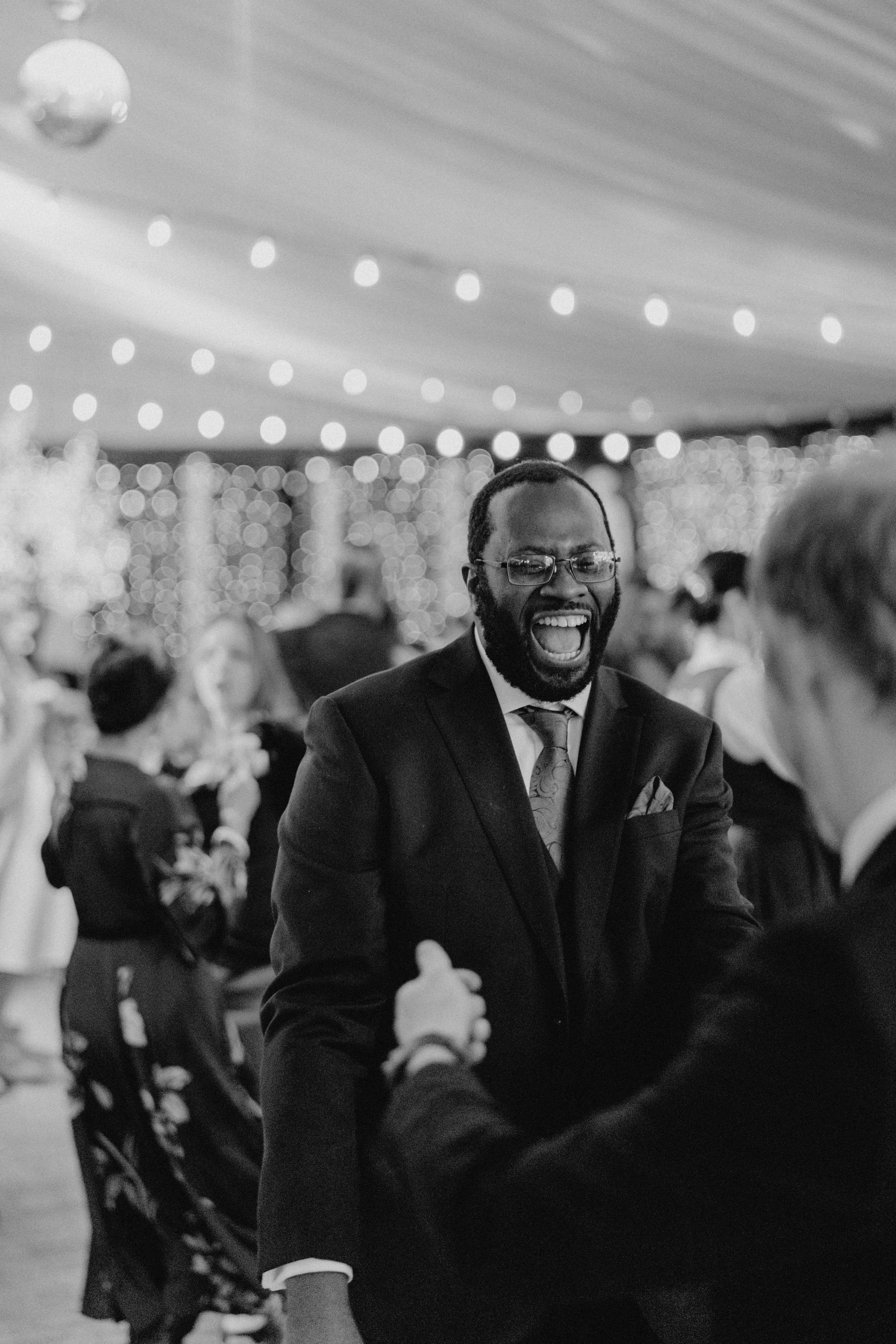 A guest enjoying a joyful moment at a wedding reception under string lights.