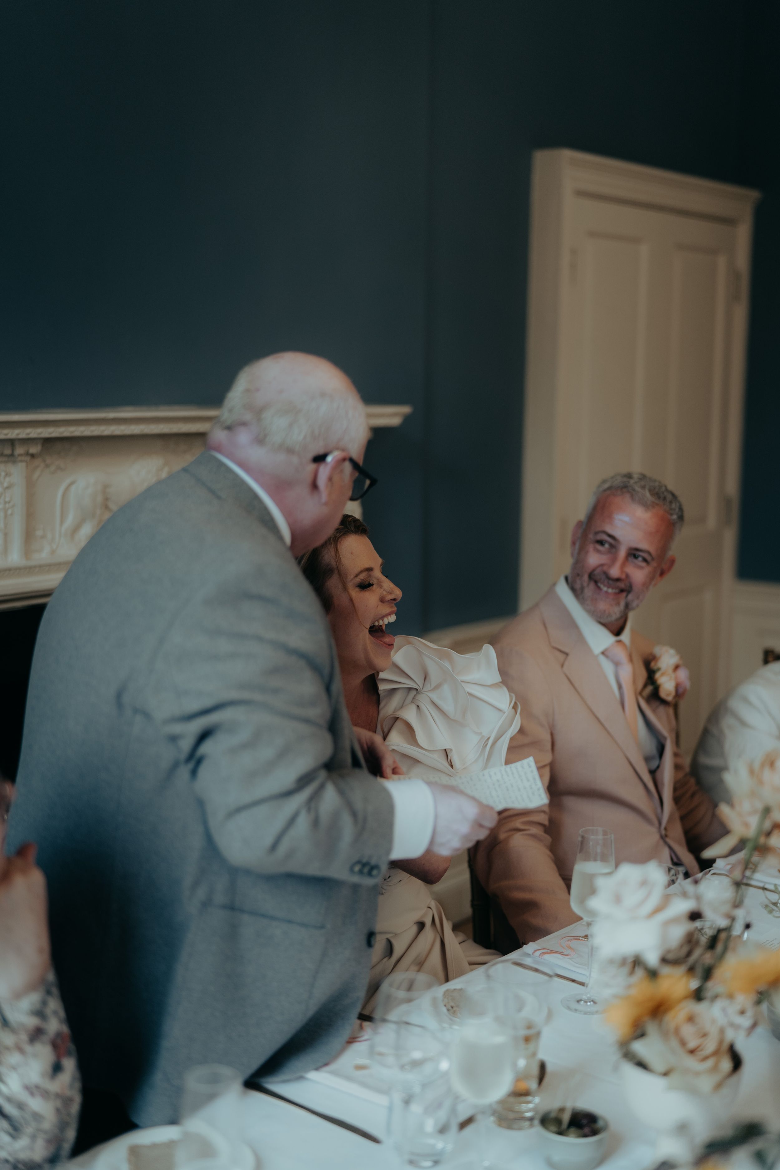 Candid moment of wedding guests sharing laughter during the reception dinner.