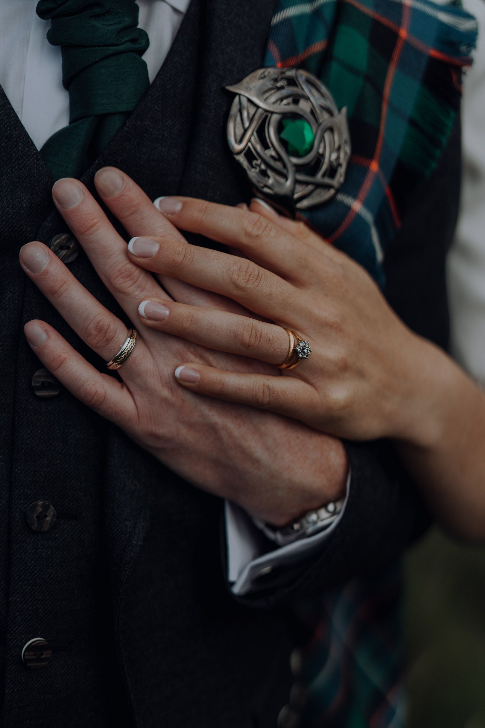 Close-up of hands showing wedding rings against tartan fabric.