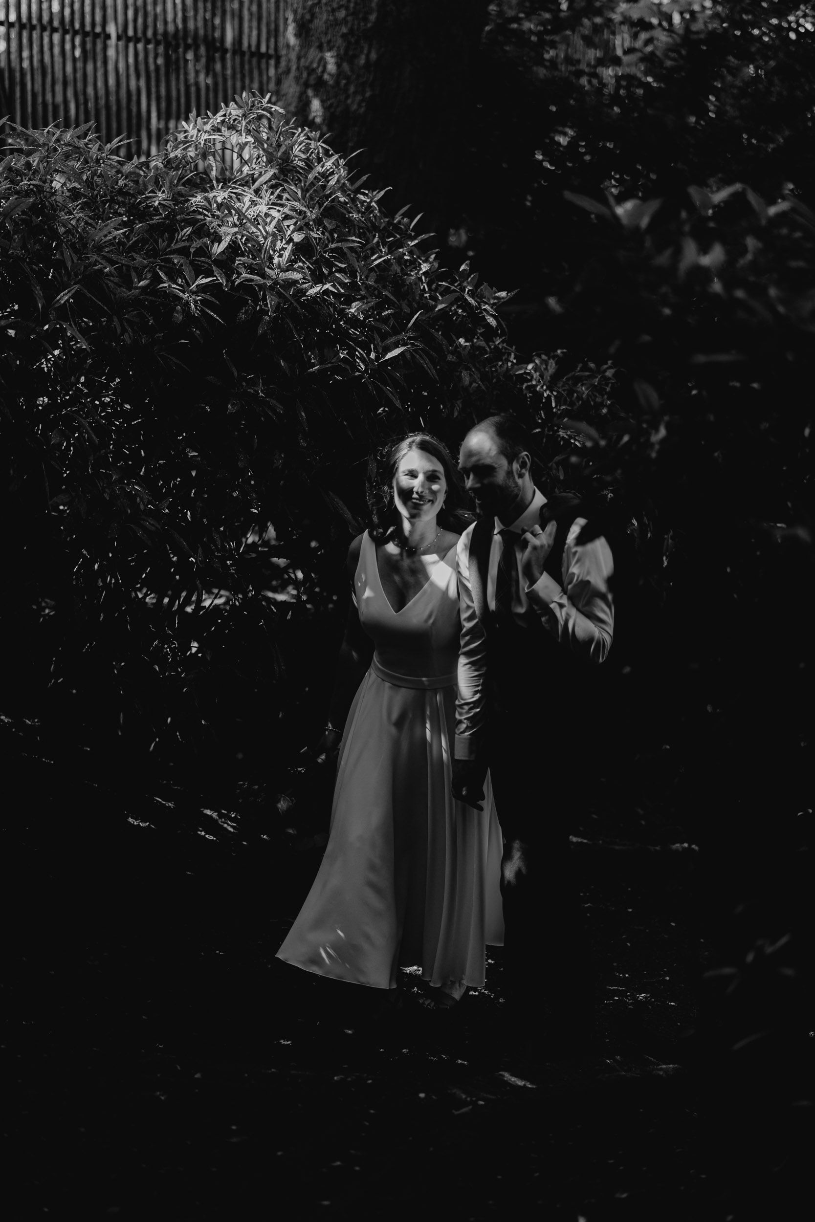 A black and white portrait of a couple in an intimate garden setting.