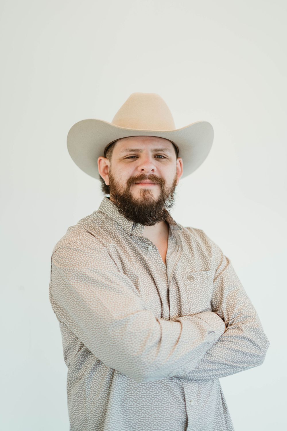 Portrait of person in western attire with cowboy hat and button down shirt.