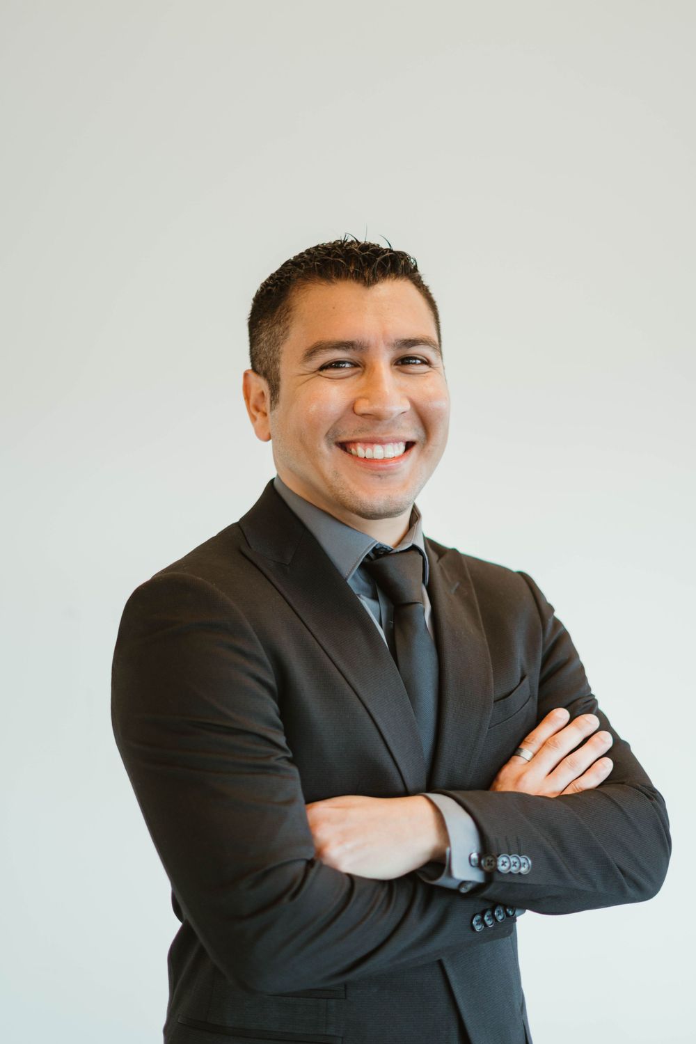 Professional headshot of person in dark suit and tie smiling confidently.