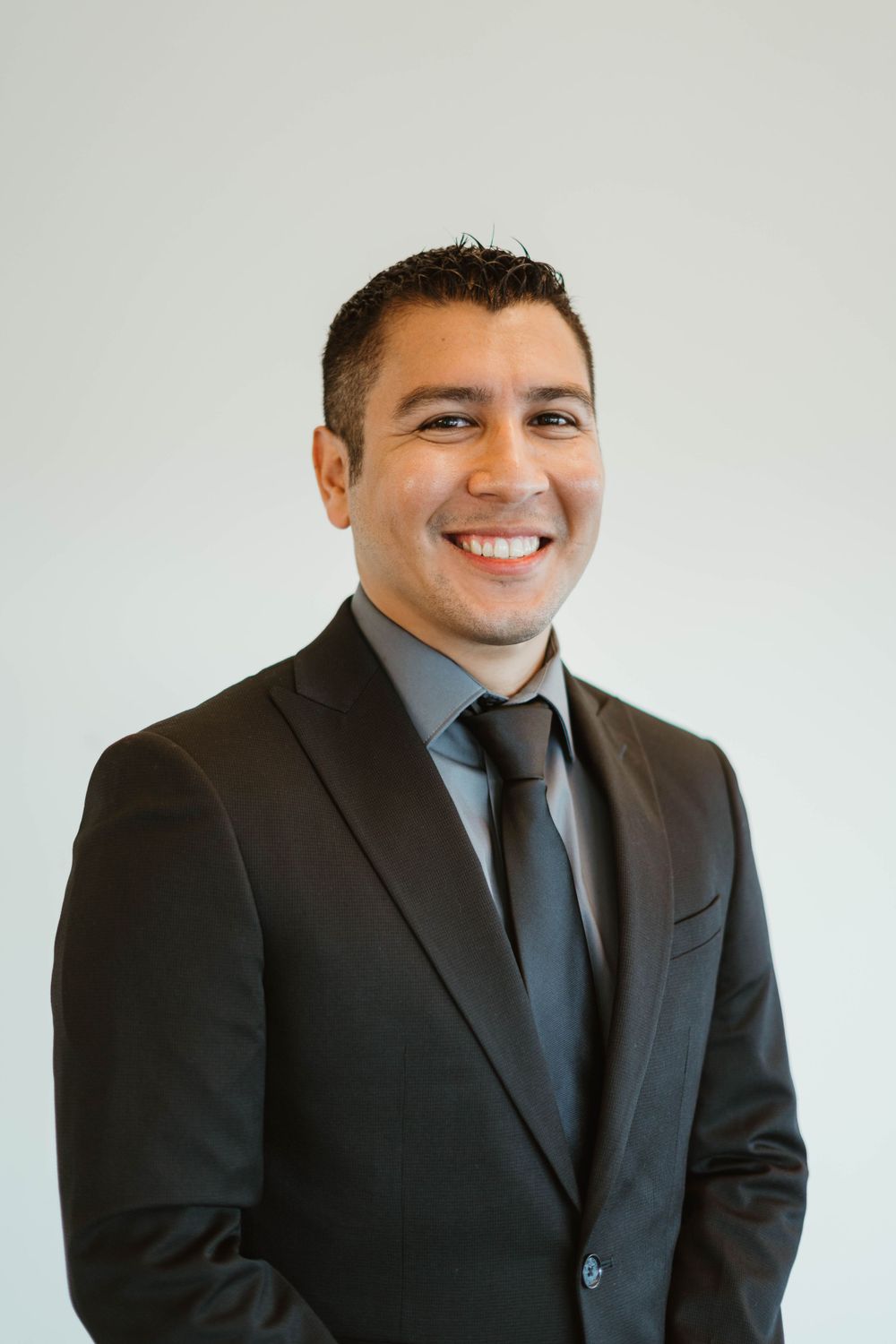 Business portrait of person in dark suit and tie with warm smile.