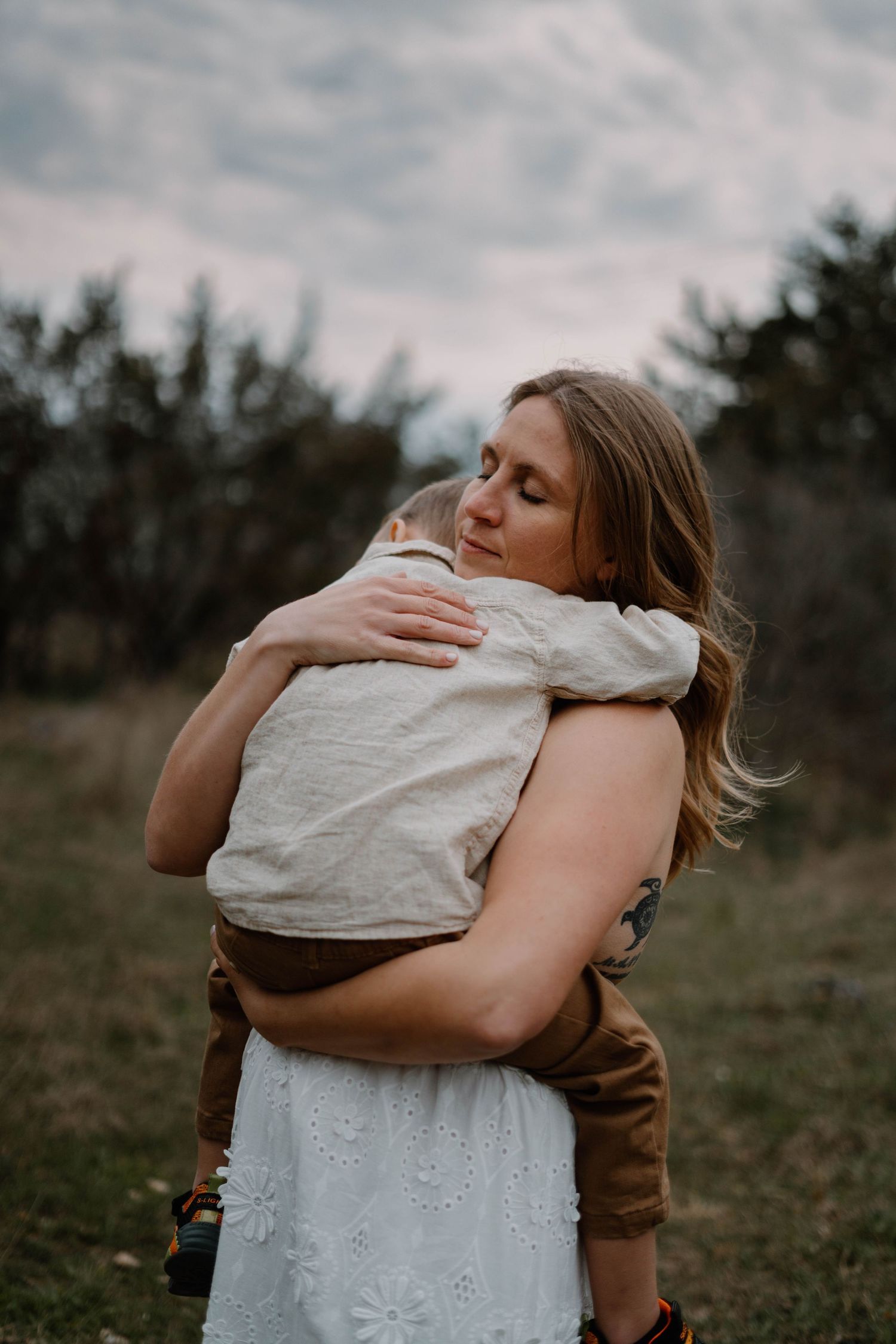 An intimate embrace between parent and child captured in moody outdoor lighting.